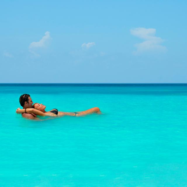 Couple floating in the crystal clear waters of Quintana Roo, Mexico