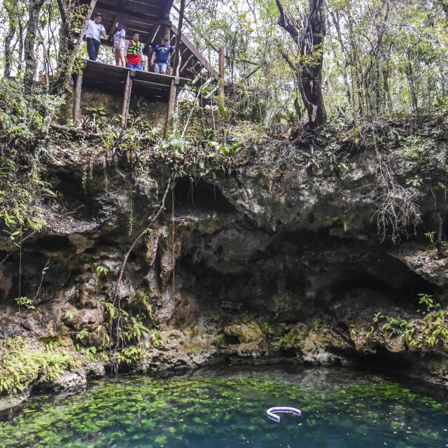 People Looking Down into Cenote with Divers
