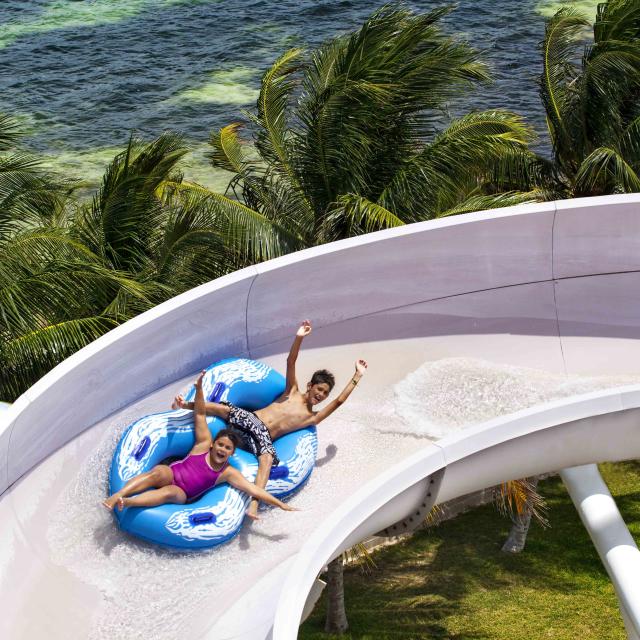 A guy and girl on a raft sliding down a water slide.