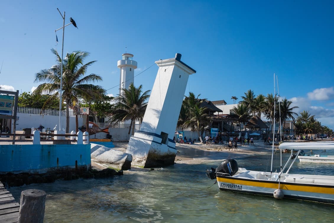 Leaning lighthouse and boats at the Puerto Morelos pier