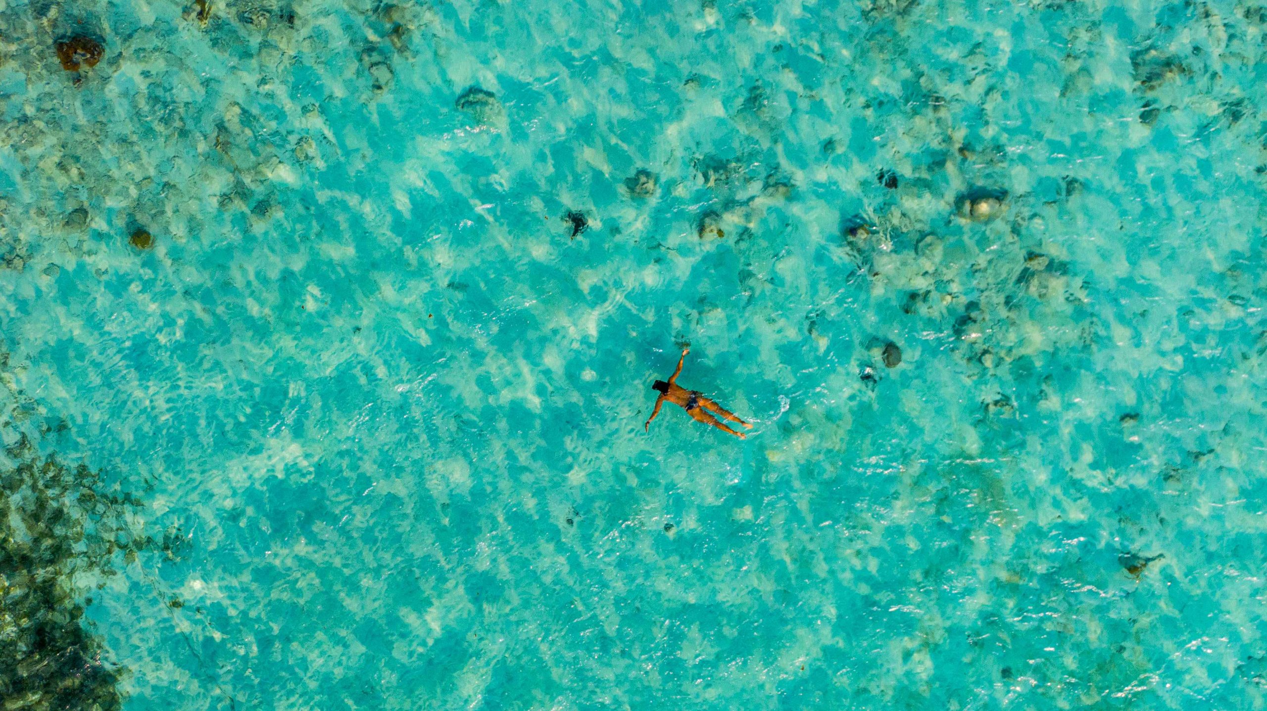 Person floating over shallow turquoise water